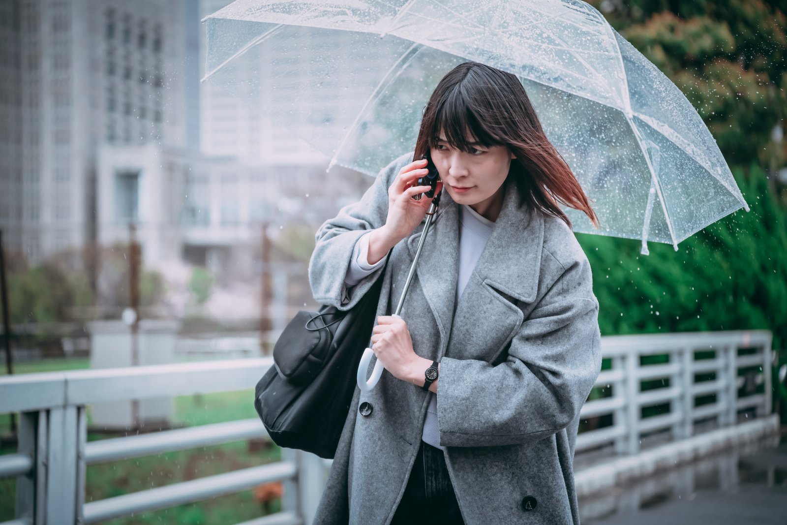 「傘を差しながら通話する女性 | フリー素材のぱくたそ」の写真［モデル：たけべともこ］