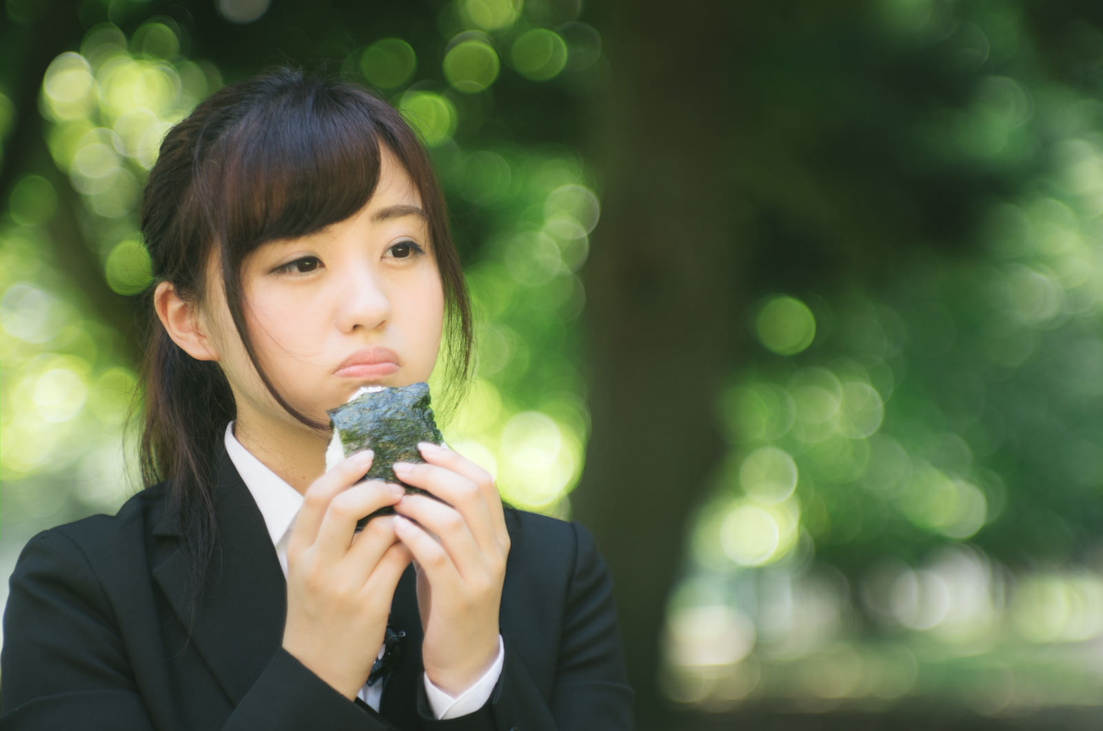 「公園で孤独におにぎりを食べる就活生」［モデル：河村友歌］