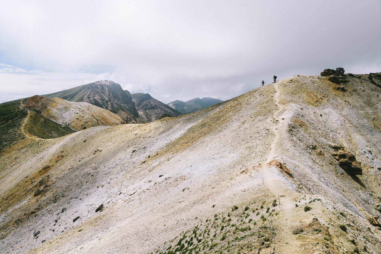 「雲が広がる稜線を歩く登山者」の写真