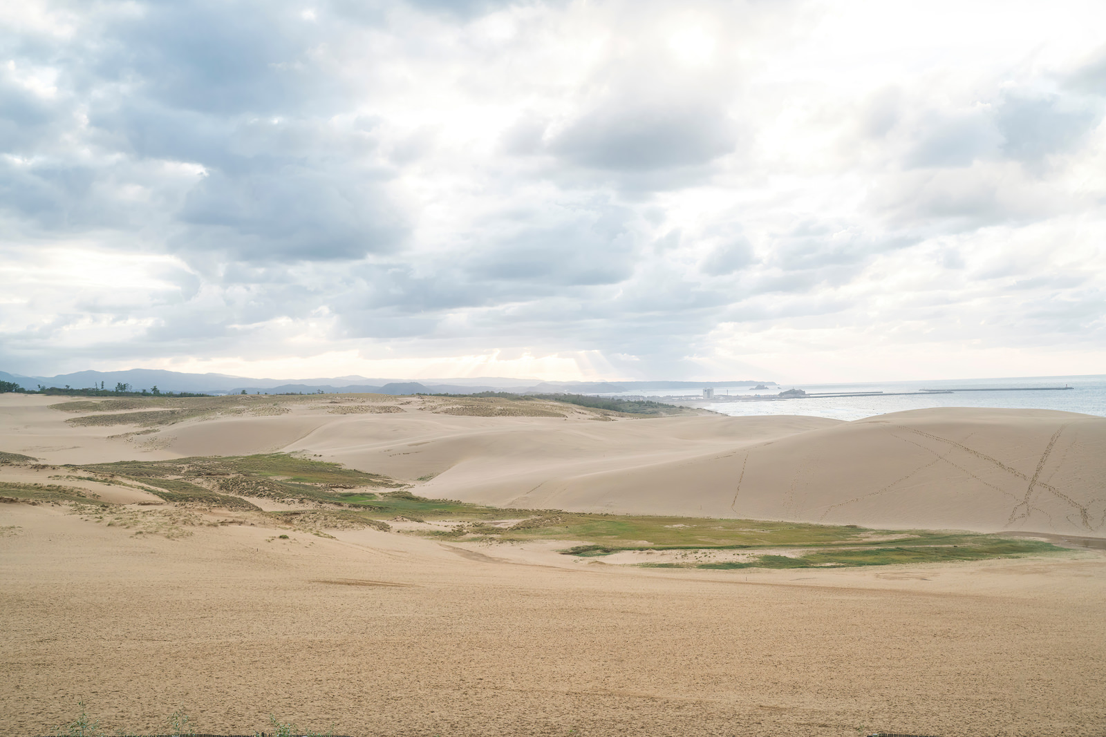 「厚い雲から差す光と鳥取砂丘 | フリー素材のぱくたそ」の写真