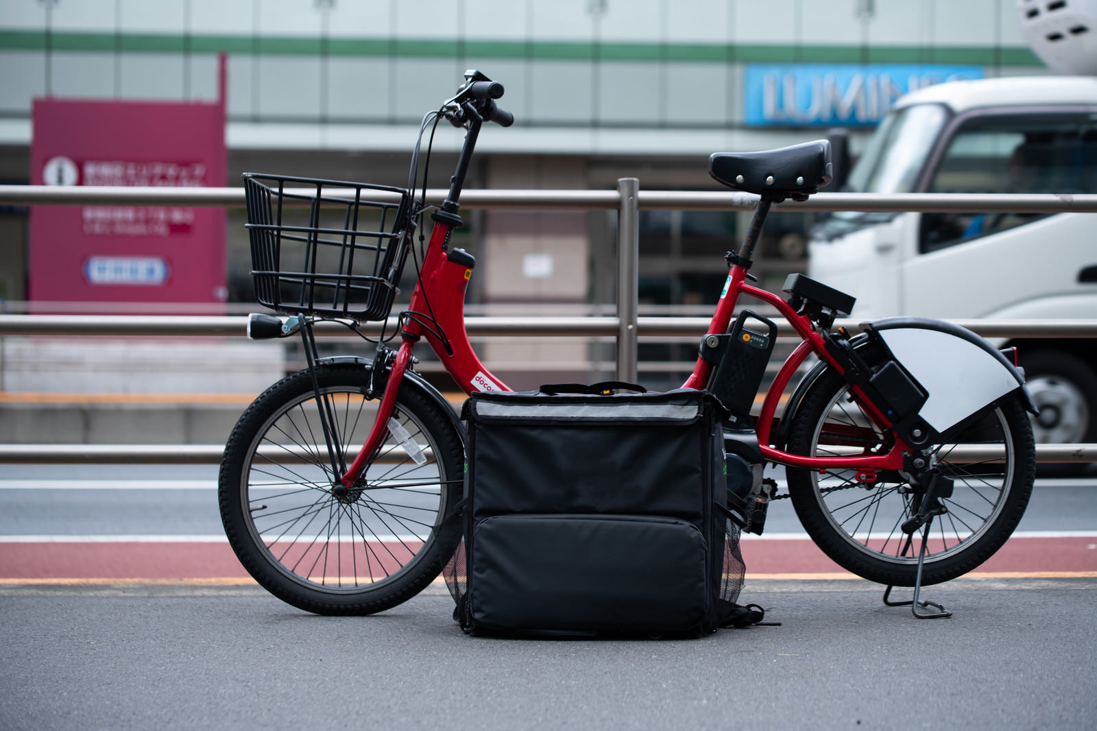 「路上に止めたフードデリバリーのバッグと自転車 | フリー素材のぱくたそ」の写真