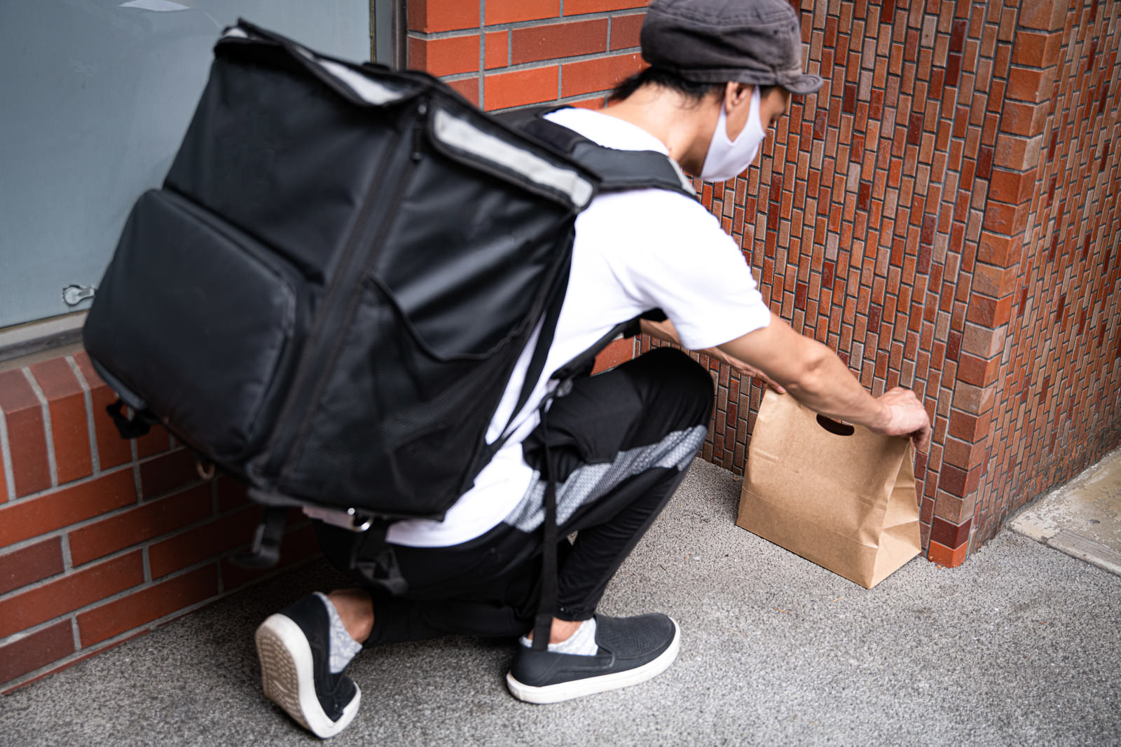 指定された場所に置き配をする配達員の写真素材 ぱくたそ