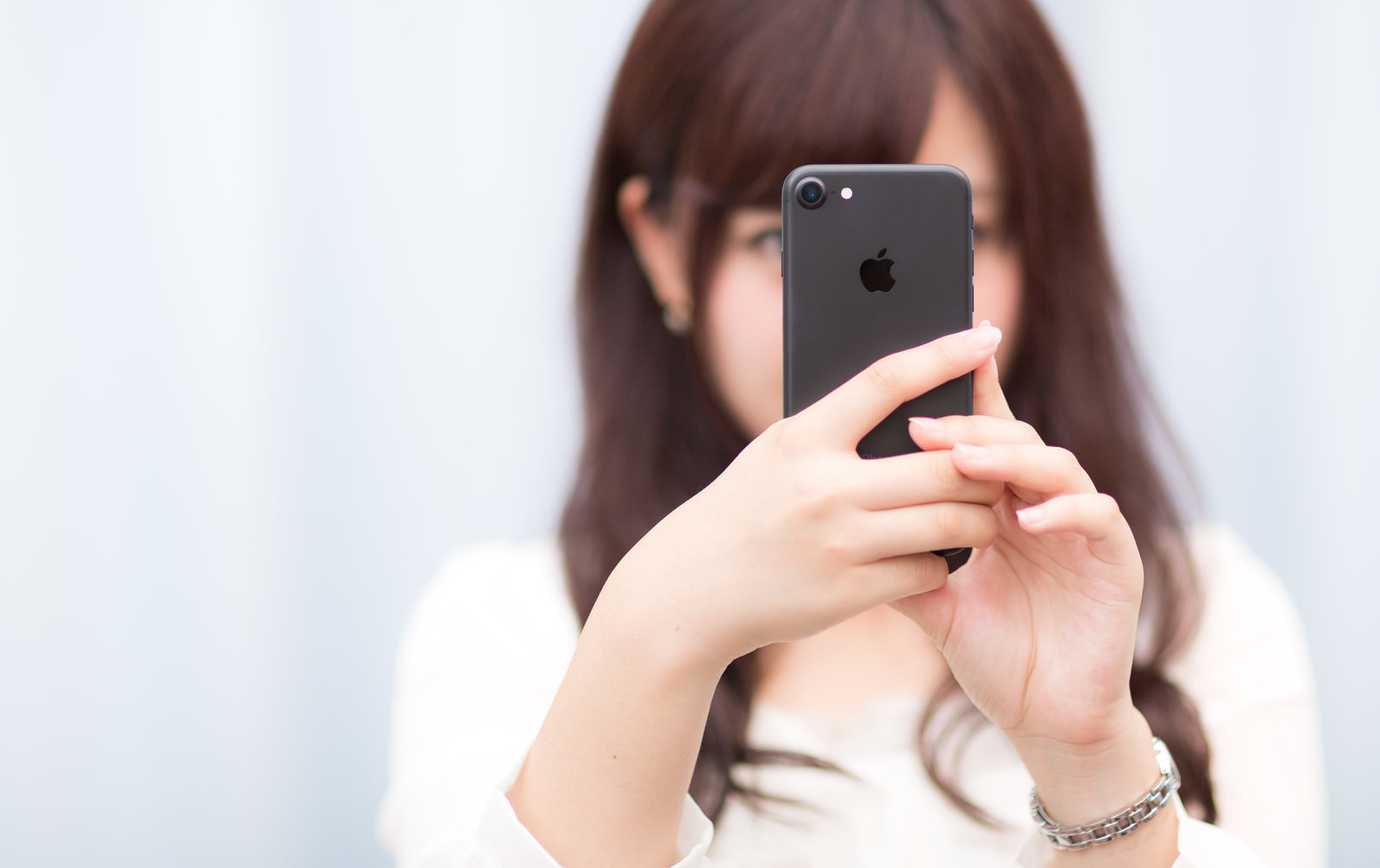 「マットブラックカラーのスマートフォンを操作する女性」の写真［モデル：河村友歌］