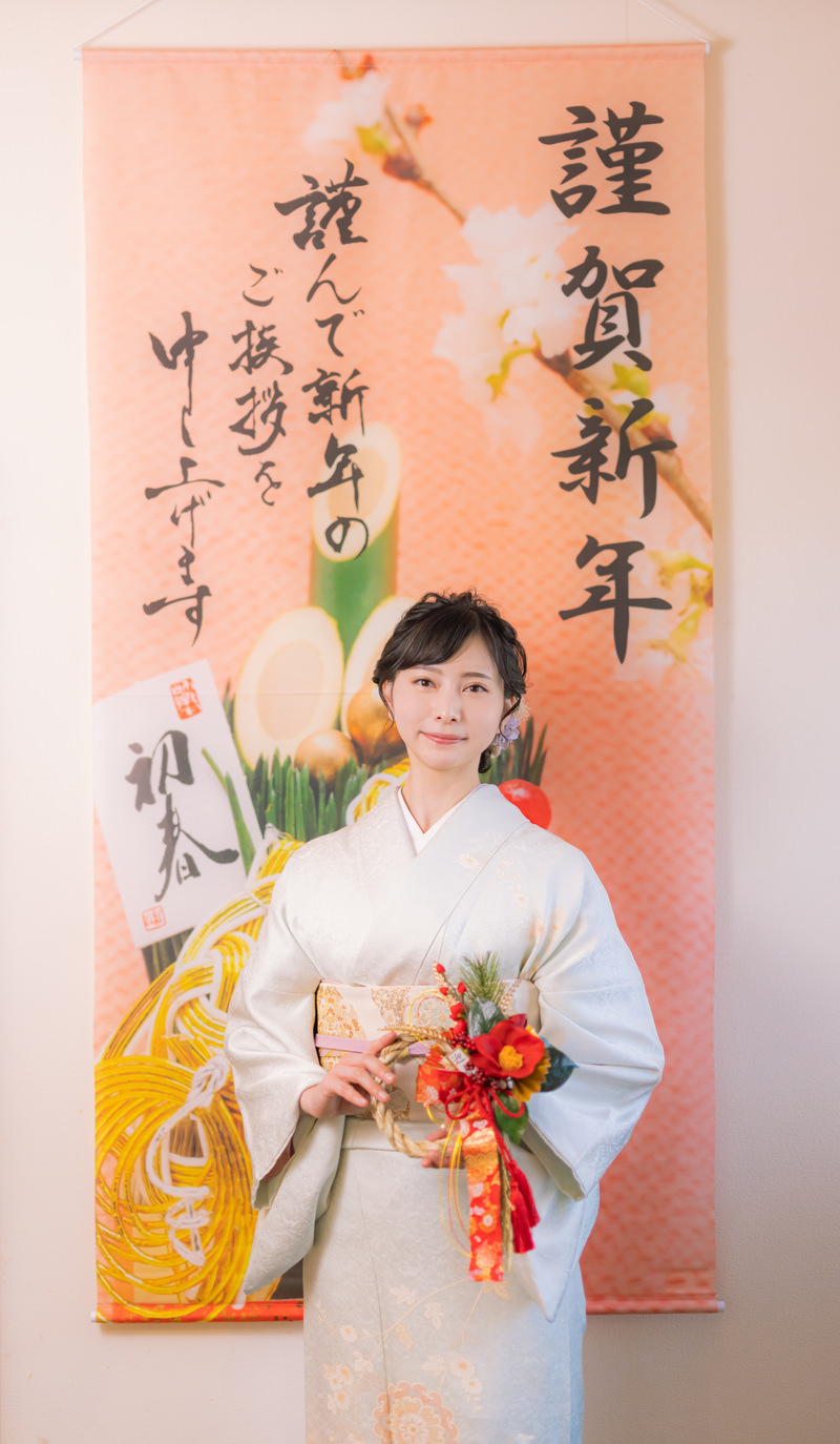 「謹賀新年の掛け軸と正月飾りを持つ着物の女性」の写真［モデル：yumiko］