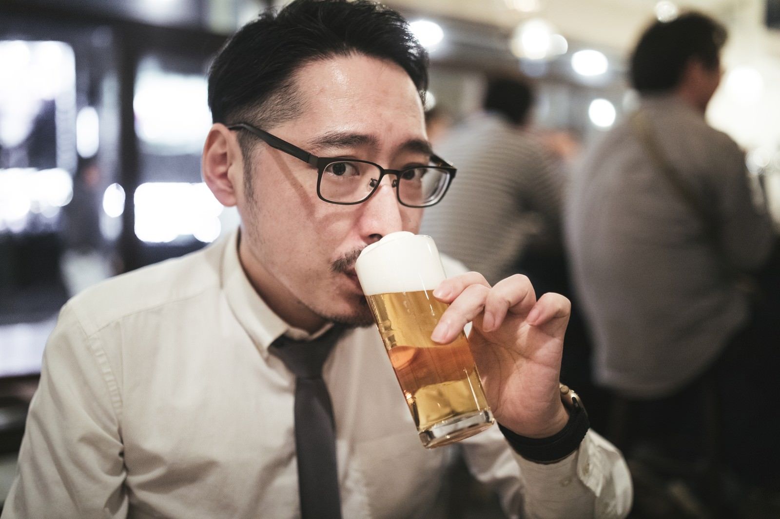 「乾杯前にこっそり飲む男性」の写真［モデル：ゆうせい］