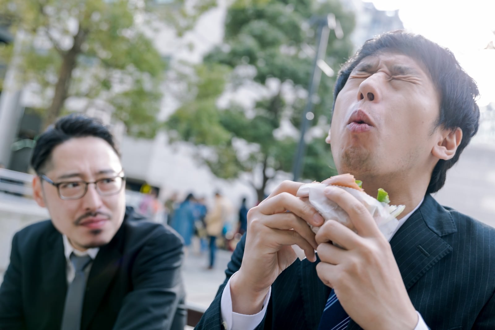 カメラが回っている時だけオーバーリアクション気味にグルメレビューする男性と横目のプロデューサーの写真を無料ダウンロード フリー素材 ぱくたそ