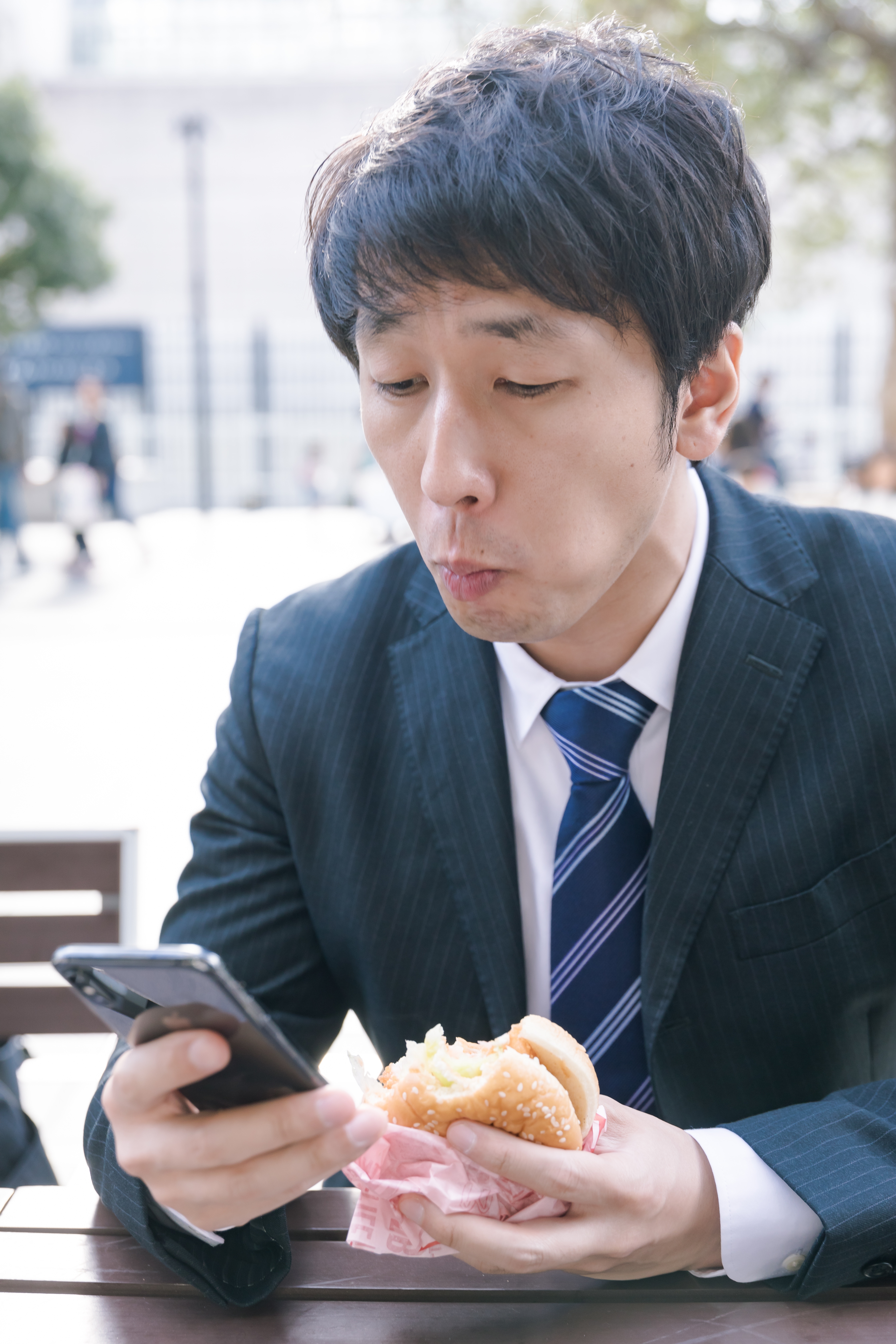 忙しなくランチにハンバーガーを食べる男性会社員の写真素材 ぱくたそ