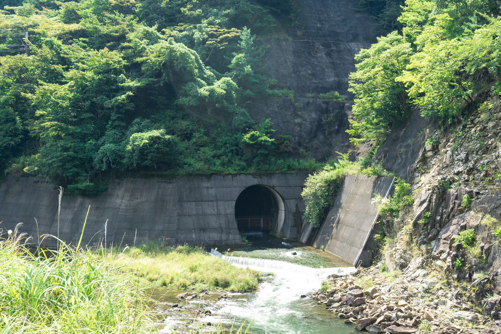 ダム下流側の青土ダム公園から見える下流への放水口の薄暗いトンネルの写真素材 ぱくたそ